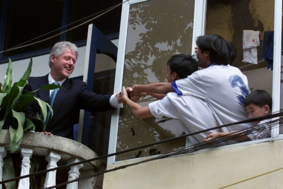 Ông Bill Clinton đến Hà Nội với tư cách tổng thống Mỹ đầu tiên thăm Việt Nam sau chiến tranh và là người quyết định bỏ cấm vận, bình thường hóa quan hệ song phương. Trong ảnh, Tổng thống Clinton bắt tay người dân từ ban công một ngôi nhà sau khi thăm Văn Miếu Quốc Tử Giám. Ảnh: AP.